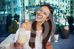 Cheerful young lady in cafÃ© drinking cocktail on open terrace