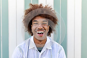 Cheerful young latino american man with curly hair laughing at camera