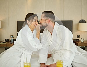 Cheerful young loving married couple, newlyweds sitting on the bed after waking up and enjoying delicious breakfast for two in a