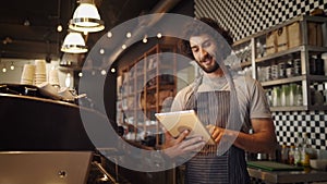 Cheerful young male cafe owner browsing for coffee recipes on internet using digital tablet