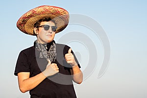 Cheerful young male person in sombrero in clear sky background.