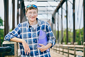 Cheerful young male student standing on bridge