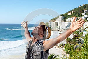 Cheerful young man with arms spread open at the beach