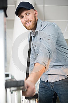 Cheerful young man carrying ladder