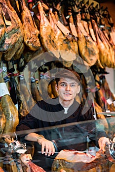 Cheerful young man cutting ham in jamoneria