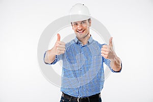 Cheerful young man engeneer in building helmet showing thumbs up