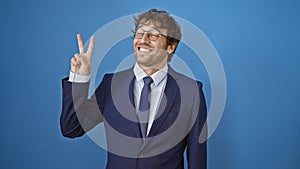 Cheerful young man in formal business suit happily pointing up, showing number two with fingers. a beaming smile across his face