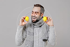 Cheerful young man in gray sweater, scarf posing isolated on grey wall background, studio portrait. Healthy fashion