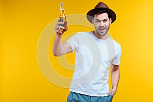 cheerful young man in hat holding glass bottle of summer drink and smiling at camera