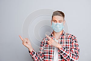 Cheerful young man pointing away wear medical safety mask on face showing data, stop pandemic corona virus prevention