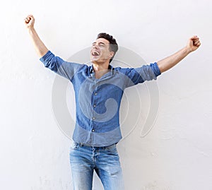 Cheerful young man with raised arms celebrating