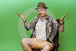 A cheerful young man is sitting in an armchair and resting