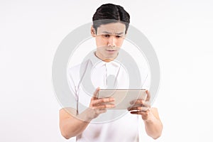 Cheerful young man standing on isolated white wall background. stared at the tablet