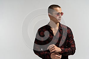 Cheerful young man in sunglesses, with blank copyspace area for slogan or advertisiment text, over grey background. photo