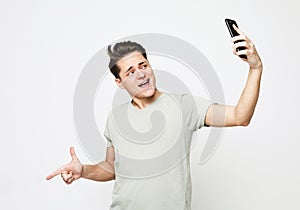 Cheerful young man taking a selfie isolated over white background