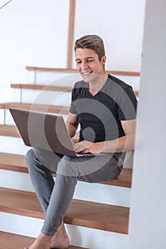Cheerful young man talking by video link using laptop