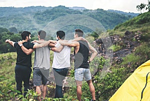 Cheerful young man traveler friends hugging with hands raise up together at nature,Enjoying backpacking concept,Back view