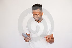 Cheerful young man using smartphone holding business card