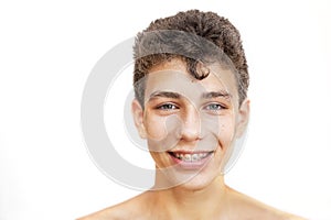 Cheerful young man with a wet face and hair on a white background. He has braces on his teeth