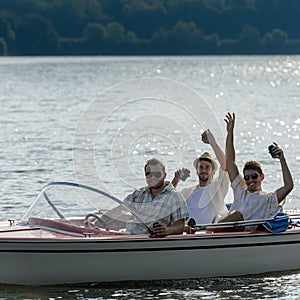 Cheerful young men drink beer speed boat