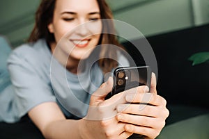 A cheerful young middle-aged woman is typing on her smartphone, watching a video, reading a message. Multitasking Maven