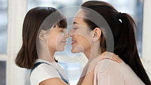 Cheerful young mother touching noses with adorable daughter.