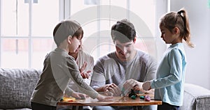 Cheerful young parents and small kids sculpting play dough at home