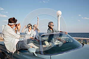 Cheerful young people driving a car and talking photos