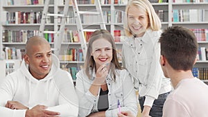 Cheerful young people enjoying talking at the college library after studying