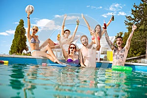 Cheerful young people in pool rejoice with raising hands with be photo