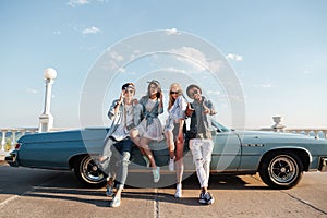 Cheerful young people standing near vintage cabriolet