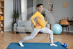 Cheerful young pregnant black woman athlete with big belly doing leg exercises and practicing yoga