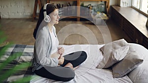 Cheerful young pregnant woman is stroking her belly and listening to music enjoying beautiful song wearing headphones