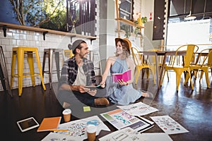 Cheerful young professionals sitting with sheets on floor