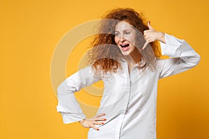 Cheerful young redhead woman girl in casual white shirt posing isolated on yellow orange background in studio. People