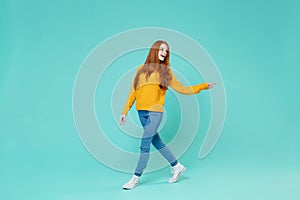 Cheerful young redhead woman girl in yellow sweater posing  on blue turquoise background studio portrait. People