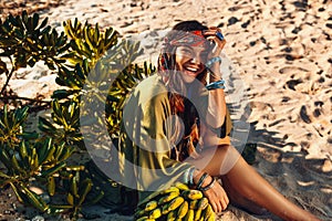 Cheerful young stylish woman with a bunch of bananas at sunset