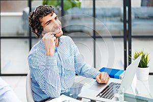 Cheerful young support phone male operator in headset, at workplace while using computer, help service and client