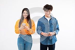 Cheerful Young Teen Couple Posing With Smartphones On White Background