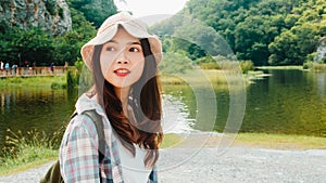 Cheerful young traveler Asian lady with backpack walking at the mountain lake.