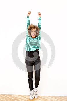 Cheerful young woman with arms raised on white background