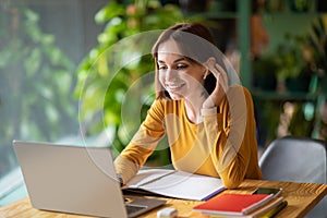 Cheerful young woman attending online business meeting, cafe interior