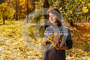 Cheerful young woman in autumn Park smiling on a Sunny day