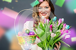 Cheerful young woman with bunny ears and Easter egg basket and tulips Flowers Looking at camera