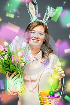 Cheerful young woman with bunny ears and Easter egg basket and tulips Flowers Looking at camera