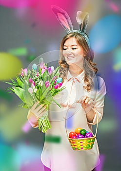 Cheerful young woman with bunny ears and Easter egg basket and tulips Flowers Looking at camera