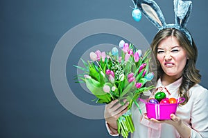 Cheerful young woman with bunny ears and Easter egg basket and tulips Flowers Looking at camera