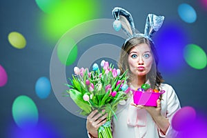 Cheerful young woman with bunny ears and Easter egg basket and tulips Flowers Looking at camera