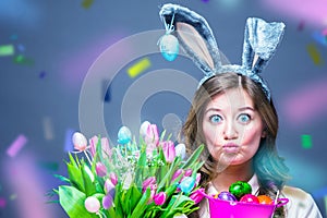 Cheerful young woman with bunny ears and Easter egg basket and tulips Flowers Looking at camera