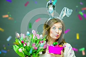 Cheerful young woman with bunny ears and Easter egg basket and tulips Flowers Looking at camera